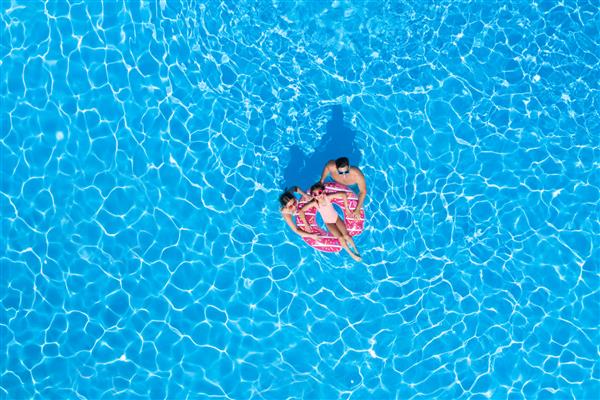 خانواده شاد با حلقه بادی در استخر شنا نمای بالا تعطیلات تابستانی