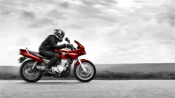 دوچرخه سواری با سرعت زیاد موتورسیکلت قرمز را سوار می کند سیاه و سفید جلوه رنگ انتخابی