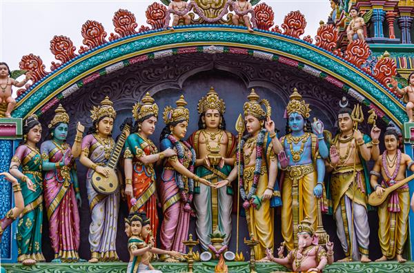 Kadirampura کارناتاکا هند - 4 نوامبر 2013 معبد سری موروگان نمای نزدیک از مجسمه‌های رنگارنگ که در کنار هم عروسی موروگان را نشان می‌دهند که در نمای بالایی زیر منظره ابری آبی قرار گرفته‌اند