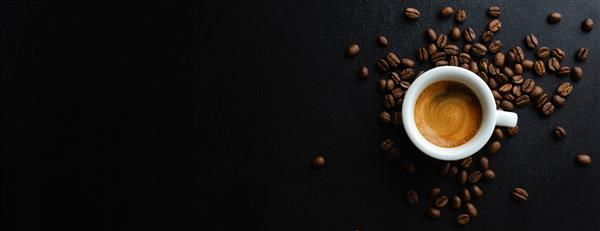 اسپرسوی خوشمزه در فنجان با دانه های قهوه و قاشق سرو می شود نمای از بالا پس زمینه تیره بنر