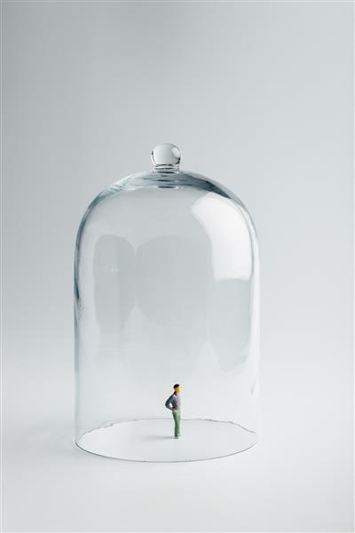 مجسمه کوچک در قرنطینه زیر یک گنبد شیشه ای در پس زمینه روشن با فضای کپی مفهوم پیشگیری از کرونا فاصله گذاری اجتماعی و قرنطینه ایزوله سازی شخصی