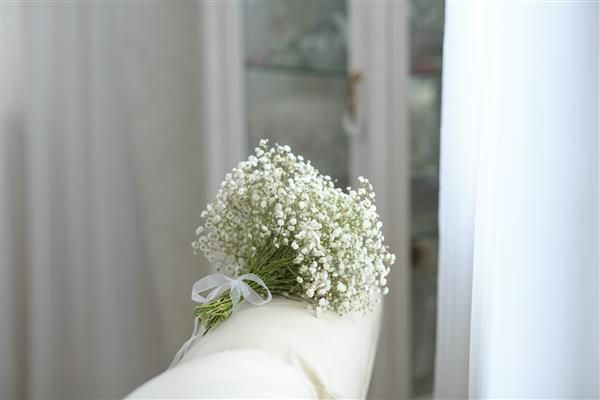 در اتاق روشن روی مبل دسته گلی از گلهای گچی سفید قرار دارد