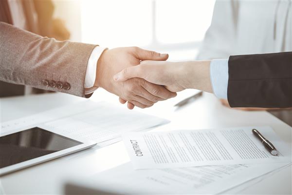 تجار دست دادن در حال اتمام امضای قرارداد در دفتر آفتابی نمای نزدیک دست دادن و بازاریابی