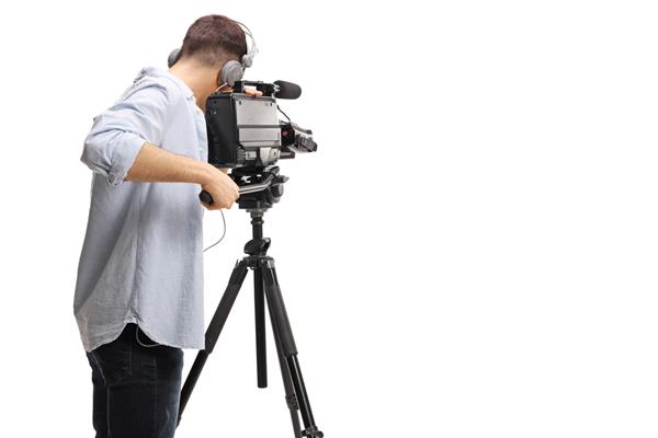 عکس پشت فیلم‌بردار در حال ضبط با دوربین حرفه‌ای روی پایه‌ای جدا شده در پس‌زمینه سفید