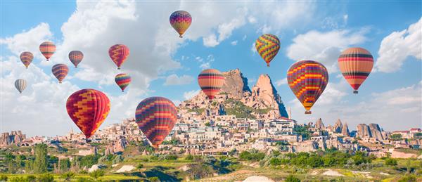 پرواز بالون هوای گرم بر فراز کاپادوکیه دیدنی قلعه اوچیسار در پس زمینه - گورمه ترکیه