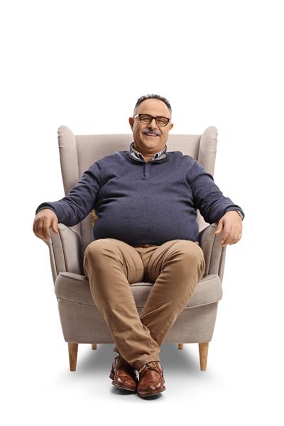 مرد بالغ شادی که روی صندلی راحتی نشسته و در پس زمینه سفید جدا شده لبخند می زند
