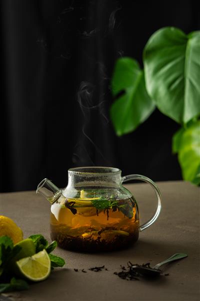 فرآیند دم کردن چای سیاه با گیاهان قوری شیشه ای با چای سیاه لیمو لیموترش و نعناع خیس شده در آب جوش بخار از بالای قوری بالا می رود