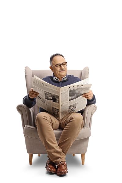 مرد بالغ در حال خواندن روزنامه روی صندلی راحتی جدا شده در زمینه سفید نشسته است