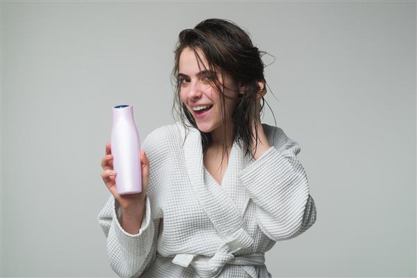 ژست زن زیبای قفقازی با موهای خیس شامپو و نرم کننده بطری نگهدارنده زن محصول مراقبت تبلیغاتی زن جوان