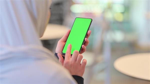 زن عرب با استفاده از گوشی هوشمند با صفحه نمایش کروم سبز