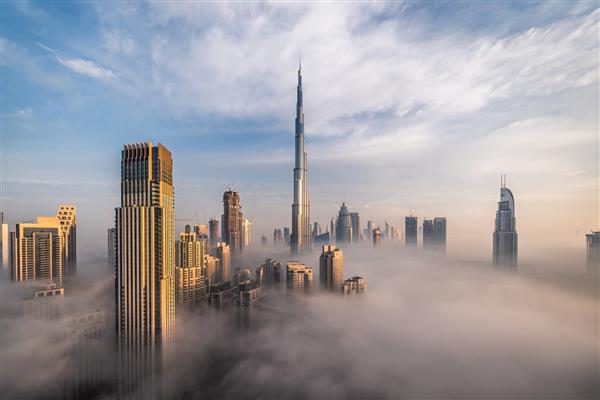 مرکز شهر دبی با آسمان خراش هایی غوطه ور در مه فکری عکس گرفته شده از منظره بی نظیر ساختمانهای بلند درخشش صبح زود