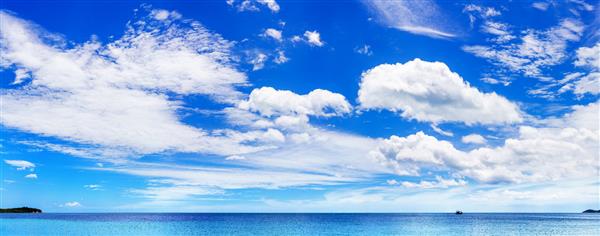 پانورامای ساحلی جزیره گرمسیری زیبا آسمان آفتابی ابرهای سفید بر فراز چشم انداز تالاب دریای آبی قایق یا کشتی در خلیج اقیانوس امواج آب تعطیلات تابستانی تعطیلات سفر منظره پانوراما دریا