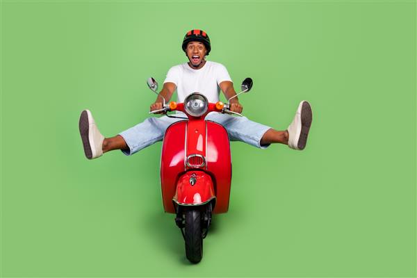 عکس تمام طول مرد جوان آفریقایی شاد و سرگرم کننده با دوچرخه سواری با فریاد رترو جدا شده روی پس زمینه سبز رنگ