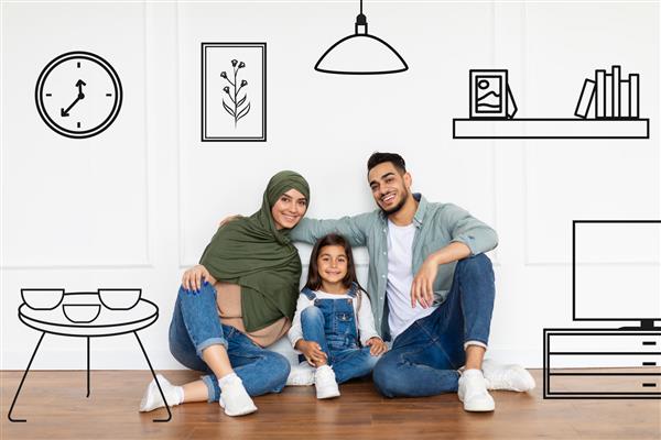مسکن خانوادگی خانواده شاد عربی نشسته روی زمین نزدیک دیوار سفید با فضای داخلی ترسیم شده سه نفر جوان خندان که خانه جدید خود را تصور می کنند والدین مسلمان در حال برنامه ریزی برای بازسازی در اتاق خالی در آغوش گرفتن