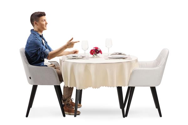 عکس نمایه یک پسر معمولی که روی میز رستوران جدا شده روی پس‌زمینه سفید نشسته است