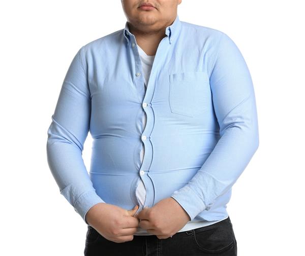 مرد چاق که تلاش می‌کند دکمه‌های پیراهن تنگ را روی پس‌زمینه سفید ببندد نزدیک