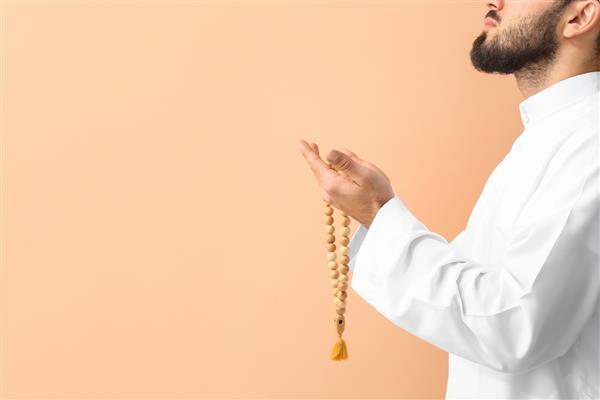 مرد جوان مسلمان در حال نماز در زمینه رنگی