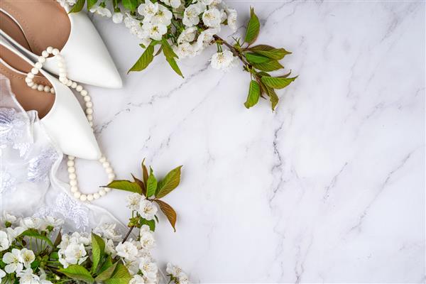 کفش های سفید عروس و شکوفه های گیلاس در بهار پس زمینه جشن عروسی مهره های سفید چادر سجاف لباس عروس