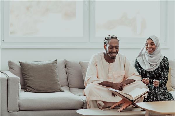 زوج مسلمان آفریقایی در خانه در ماه رمضان در حال خواندن قرآن کتاب اسلام مقدس