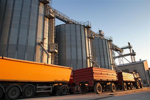 تراکتور و کامیون در کنار سیلوهای غلات سیلوها و سطل های فولادی تجاری برای نگهداری غلات بارگیری ذرت گندم یا سویا در سیلوهای فلزی برای نگهداری پس از برداشت