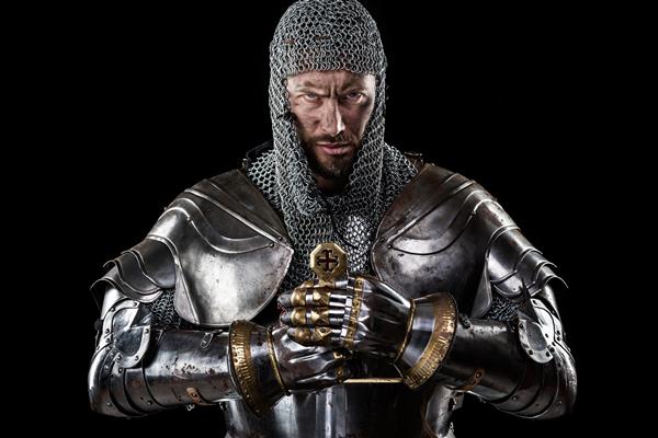 پرتره جنگجو با چهره کثیف قرون وسطایی با زره زنجیر و صلیب قرمز روی شمشیر پس زمینه سیاه