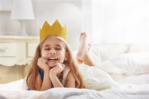 دختر بچه ناز با لباس شاهزاده خانم کودک زیبا که برای یک مهمانی لباس آماده می شود ملکه زیبا با تاج طلایی