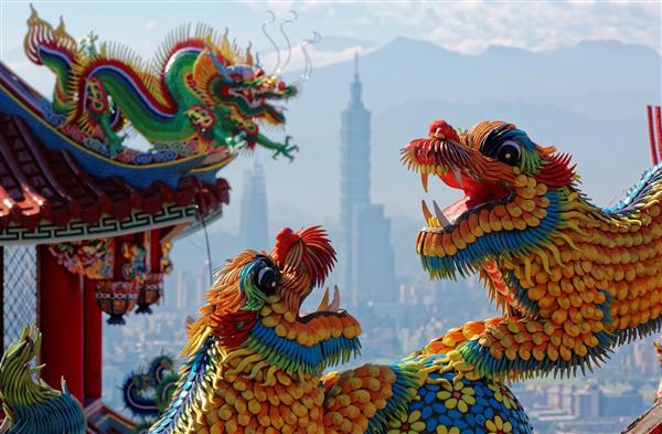 سقف های رنگارنگ معبد تایوانی تزئین شده با مجسمه های حیوانات مقدس و فرخنده اژدها و شیرها در هنر موزاییک سنتی و برج 101 تایپه در پس زمینه شهر تایپه تایوان آسیا