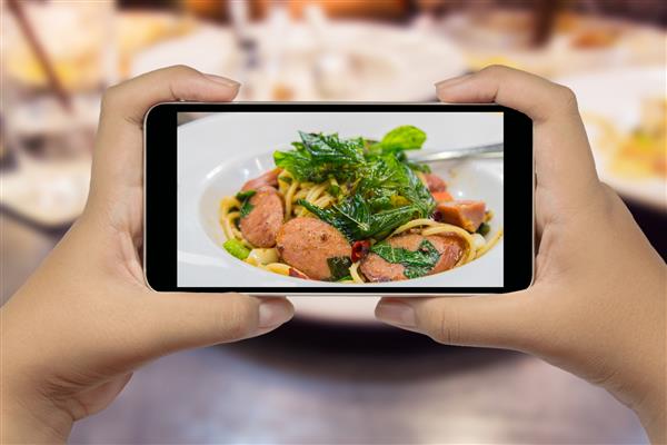دست در دست گرفتن یک تلفن هوشمند عکاسی از غذا
