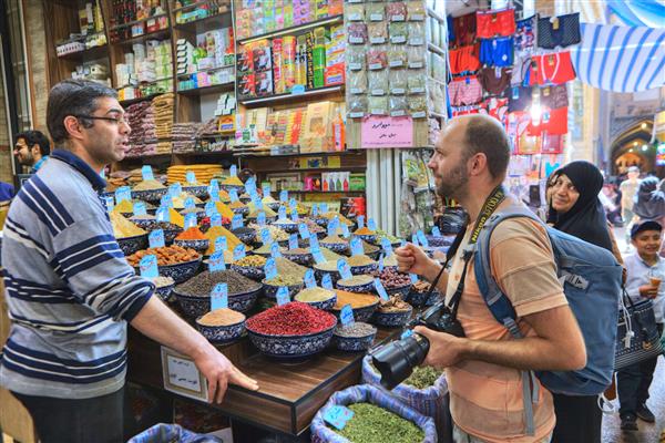 استان فارس شیراز ایران - 19 آوریل 2017 فروشنده ایرانی ادویه و خشکبار به گردشگر در انتخاب کالا برای خرید کمک می کند