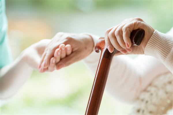استفاده سالمند از عصای چوبی در حین توانبخشی در بیمارستان دوستانه