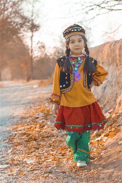 دختر بچه با لباس محلی در منظره پاییزی