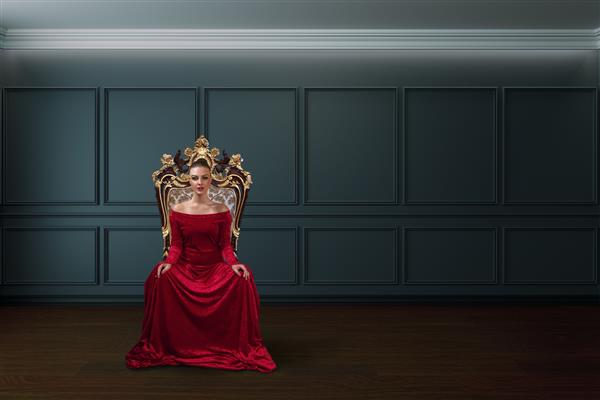 زنی با لباس مجلسی قرمز مجلل که بر تخت ملکه نشسته است