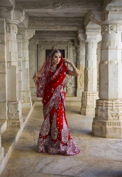 ماهارانی زیبا زن جوان هندی با لباس ساری عروس قرمز با جواهرات شرقی عروس دختر زیبای هندی در ساری عروسی عروس هندی در معبد باستانی جین راناکپور روز عروسی