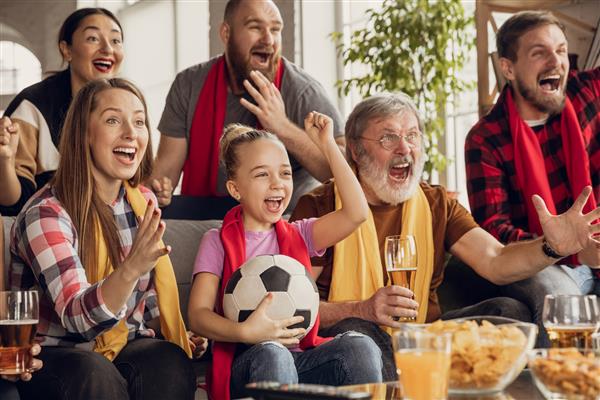 خانواده بزرگ هیجان زده و شاد در حال تماشای فوتبال مسابقه فوتبال روی کاناپه در خانه تشویق احساسی هواداران تیم ملی محبوب لذت بردن از پدربزرگ و مادربزرگ تا فرزندان ورزش تلویزیون قهرمانی