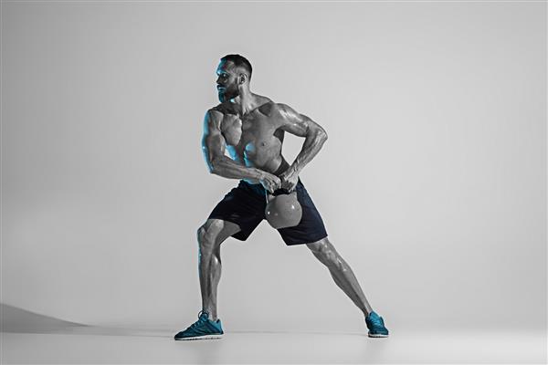 به بهترین خود تمرین بدنساز جوان قفقازی بر روی پس زمینه استودیو در نور نئون مدل مردانه عضلانی با وزن مفهوم ورزش بدنسازی سبک زندگی سالم حرکت و عمل