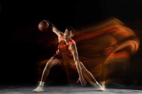 آماده بسکتبالیست جوان عضلانی عرب در حال حرکت حرکت ایزوله روی مشکی در نور مختلط