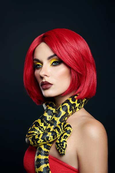 زن زیبا با موهای قرمز و مار پیتون زرد به دور گردنش آرایش چشم زیبایی روشن حرفه ای رژلب زرد قرمز شرابی