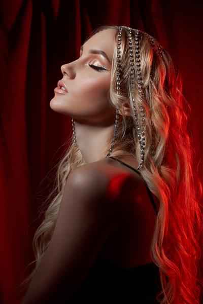 زن بلوند زیبا با موهای بلند روی زمینه مخملی قرمز زیورآلات مو روی سر یک زن آرایش مدرن و پیکان روی چشم