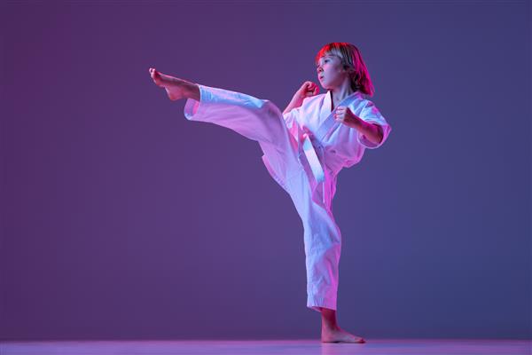 عکس دوامیک از تمرین کاراته‌کا پسر کوچک که روی پس‌زمینه بنفش در مفهوم هنرهای رزمی نئون جدا شده است