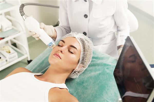 پزشک و مراجعه کننده زن زیبا در حین درمان لیفت با رادیوفرکوئنسی در کلینیک زیبایی پزشکی