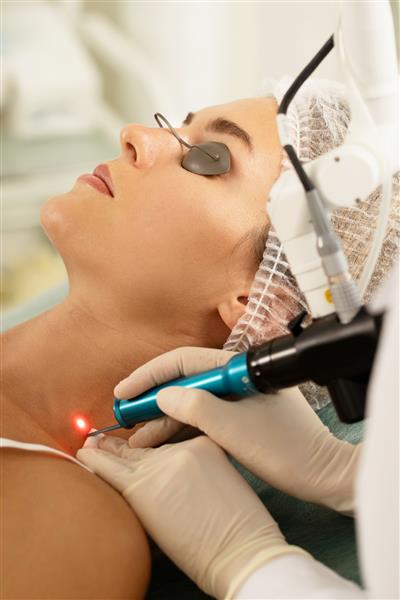 مراجعه کننده زن در حین حذف لیزر رنگدانه یا خال مادرزادی در یک کلینیک زیبایی پزشکی