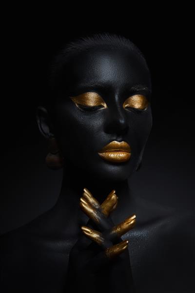 زن زیبایی که با رنگ پوست مشکی نقاشی شده است پلک های آرایش طلایی لب ناخن های نوک انگشتان با رنگ طلایی آرایش طلایی حرفه ای