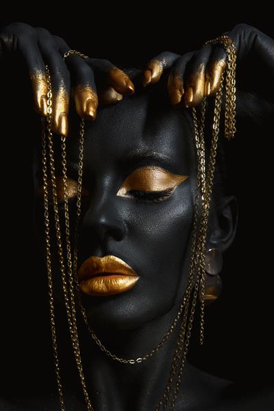 زن زیبایی با رنگ پوست مشکی نقاشی شده است زنجیر طلایی در دستان و دور گردنش آرایش طلایی لب پلک ناخن نوک انگشتان در رنگ طلایی آرایش حرفه ای