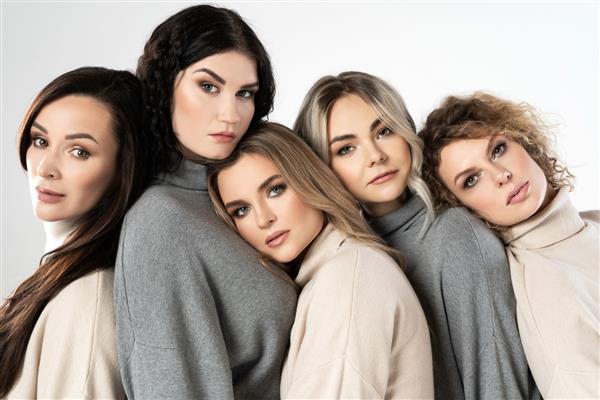 گروهی از زنان مختلف که جامپرهای یقه اسکی پوشیده اند در پس زمینه خاکستری دوستی تنوع و مفاهیم دیگر