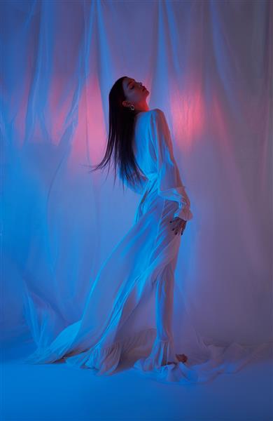زن مد زیبا با لباس سفید روشن در کنسرت آزادی استودیو به رنگ نئون لباس سبک مد سبک روی پاهای بلند زنانه اندام