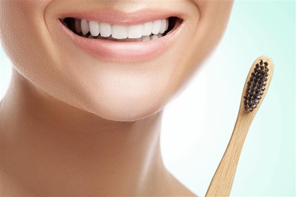 دهان زن با دندان های سفید و مسواک بامبو
