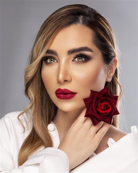 مدل زن زیبای ایرانی با موهای روشن و لباس سفید که رز قرمز کنار صورتش دارد