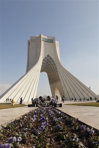 برج آزادی تهران و مرد درحال گل کاری و زیباسازی شهر