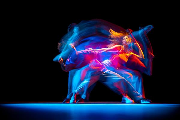 پرتره پویا از مرد و زن جوان در حال رقص هیپوپ جدا شده روی پس‌زمینه سیاه با جلوه نورهای مختلط