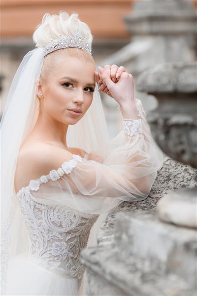 نمای کناری عروس شیک پوش با لباس سفید شیک در خیابان که به دوربین نگاه می کند